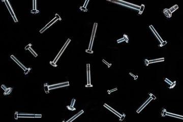 top view of scattered metal bolts pattern isolated on black