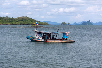 Fototapeta na wymiar Traditional long boat sailing by the island in Thailand.