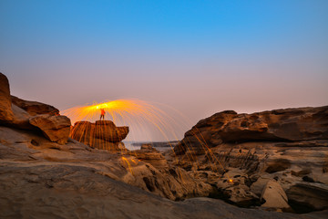 Swing fire dancing show.Swirl Steel Wool light Photography over the rock and water at night Sam Phan Bok.Photo by long exposure with noise and grain.