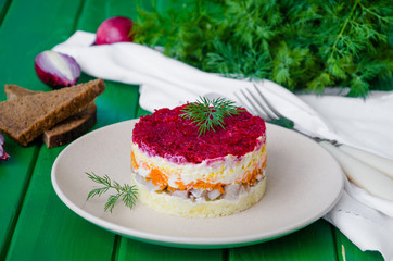 Traditional festive Russian salad herring under a fur coat on the plate. Salad with salty fish and boiled vegetables. 