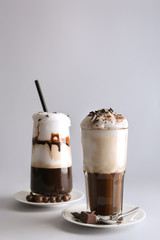 Glasses of tasty frappe coffee on grey background