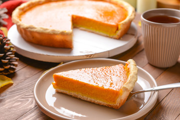 Plate with piece of tasty pumpkin pie on table