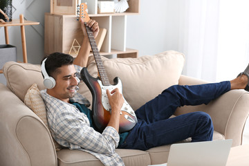 Handsome man playing guitar at home