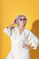 Curly-haired pretty woman posing near yellow background