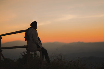 silhouette woman sitting on mountain in evening