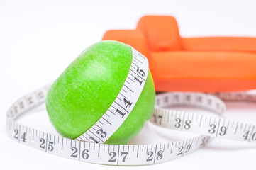 Diet diabetes weight loss concept with tape measure organic green apple and yellow dumbbels on a...