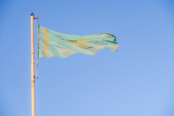 Flag of Kazakhstan against the blue sky.