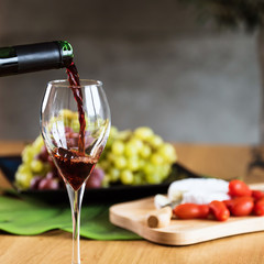 Obraz premium Waiter pouring red wine into wineglass. 