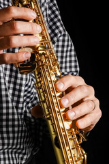 Naklejka premium soprano saxophone in hands on a black background