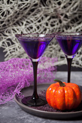 Two glasses with purple cocktail, pumpkin for Halloween party on the dark background