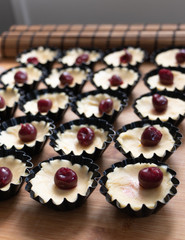 Small tarts with cherry and whipped egg whites and pistachio filling in metal forms before baking showing the process2