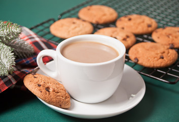 Cup of tea, homemade cookie, Christmas gift boxes and Christmas decor on the green background.