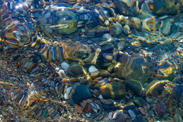 Beautiful pebbles and sea stones under the ripples of water, top view