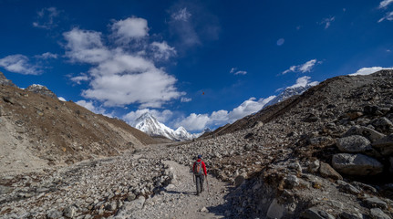 Lone trekker walking away through the Himalaya mountains of Nepal