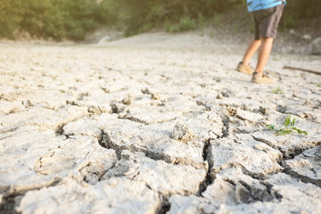 Dry lagoon due to lack of rain after drought, hot summer. Kid playing