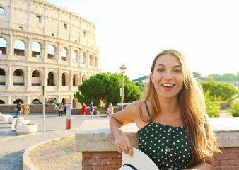 Happy smiling beautiful tourist girl in Rome with Colosseum on the background at sunset. Summer...