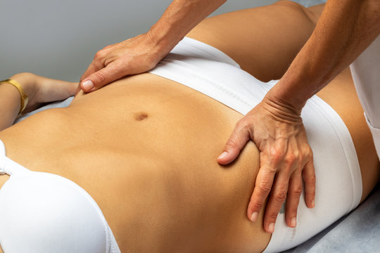 Physiotherapist manipulating female abdomen.