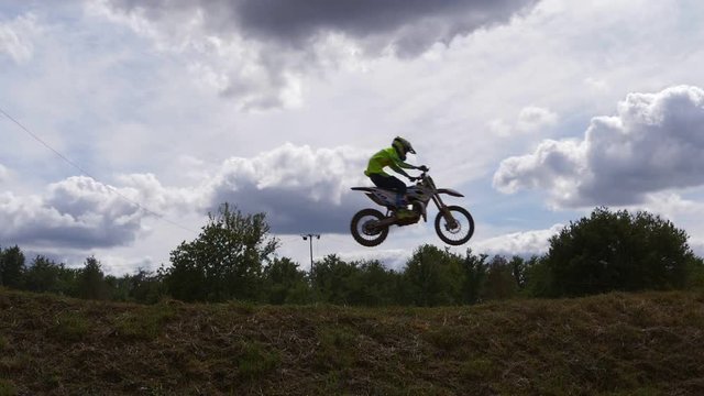 Silhouette shot of motocross racer jumping above sky. Slow motion.