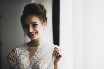 Gorgeous bride in robe posing and preparing for the wedding ceremony face in a room