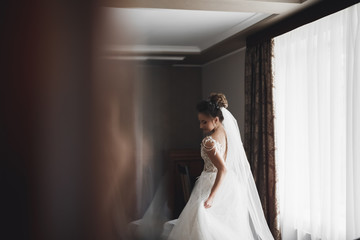 Gorgeous bride in robe posing and preparing for the wedding ceremony face in a room