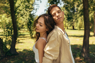 Fototapeta premium Portrait of romantic couple in love dating outdoors at the park on a sunny day. Happy couple in love embracing each other with closed eyes. Date day. Valentine day