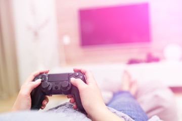 POV Woman lying on the coach in front of TV and holding in hands wireless game controller. Game addiction concept. © B@rmaley