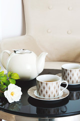 Two cups and tea cattle on a table.