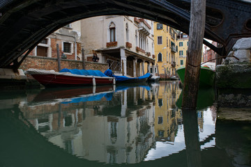 Low angle view of parked boats parked along water canal with reflection in Venice
