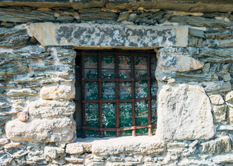 closed window in stone wall with iron railings in medieval hermitage