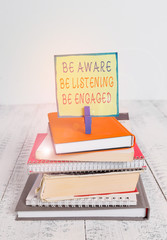 Word writing text Be Aware Be Listening Be Engaged. Business photo showcasing take attention to actions or speakers pile stacked books notebook pin clothespin colored reminder white wooden