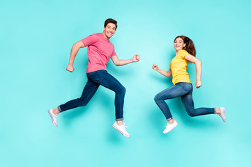 Fototapeta na wymiar Full length body size profile side view of nice attractive sporty cheerful couple running jumping in air having fun holiday spring isolated over bright vivid shine vibrant green turquoise background