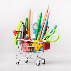 Close up of shopping cart with office supplies isolated on white
