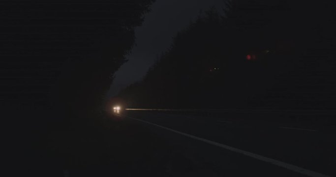 4K Car with Headlights driving through Scottish Glen Coe Mountain Highlands in the night. A Forest and Mountanious Tourist Nature destination within Rural Scotland in the Summer.
