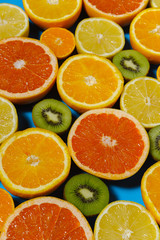 Fresh summer fruits on blue background. Healthy food concept. Flat lay. Tropical summer mix grapefruit, orange, mandarin, kiwi, lemon