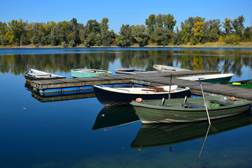 Obraz premium Autumn landscape with a lake, a boat bridge and some boats.