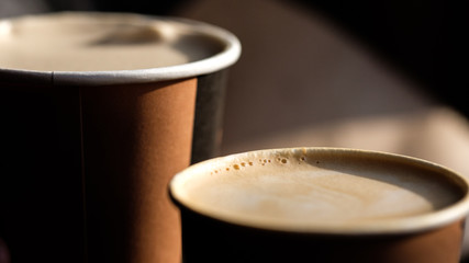 two cups of coffee in takeaway paper cups. soft light