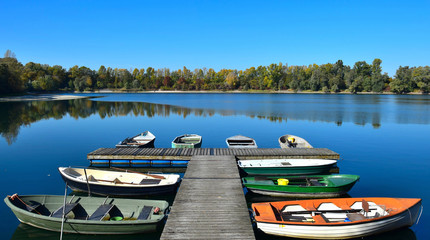 Autumn landscape with a lake, a boat bridge and some boats.