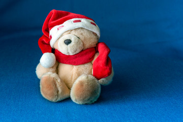 Toy Bear in Santa's hat as a New Year's gift on a blue background