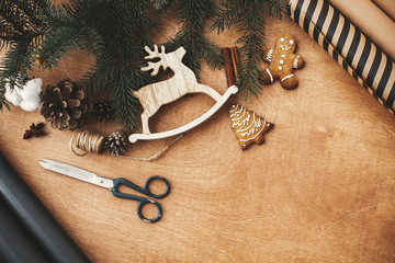 Christmas rustic flat lay. Stylish wrapping paper, wooden reindeer, gingerbread cookies, pine...