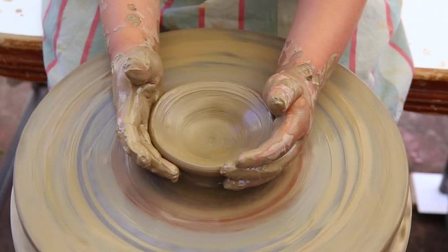 Young potters hands forming clay pot, learn to work on pottery wheel