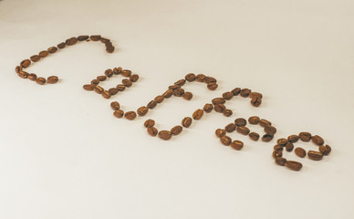 Coffee word made of roasted coffee beans on white surface close up