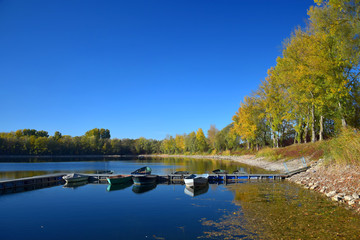 Obraz premium Autumn landscape with a lake, a boat bridge and some boats.
