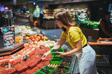 young woman taking berries from store shelf