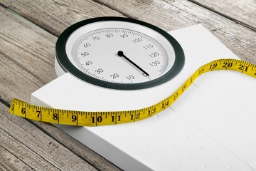 Bathroom scale with a measuring tape on background