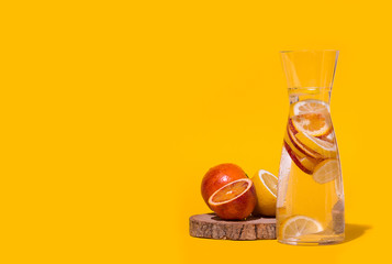 Tall water tray with lemons and oranges on a yellow backdrop