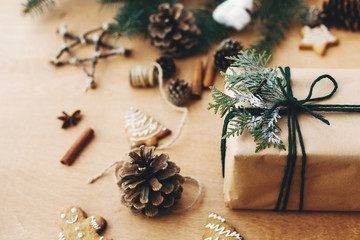 Stylish rustic christmas gifts box with cedar branch on  rural wooden table with pine cones,...