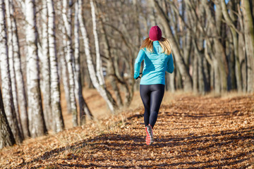 Back view of running girl in fall park in morning