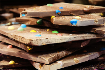Chocolate filled with colorful candies background. Sweet temptation and indulgence concept. Selective focus.