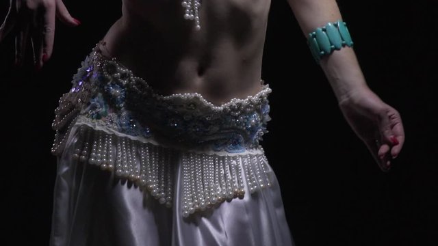 Close up of the lower body of a woman belly dancing in white dress