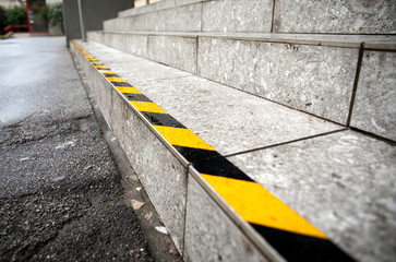 Yellow anti slip warning tape on stairs outdoors for safety. Public building